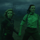 Loki (Tom Hiddleston) and Sylvie (Sophia Di Martino) are bathed in green while holding hands.